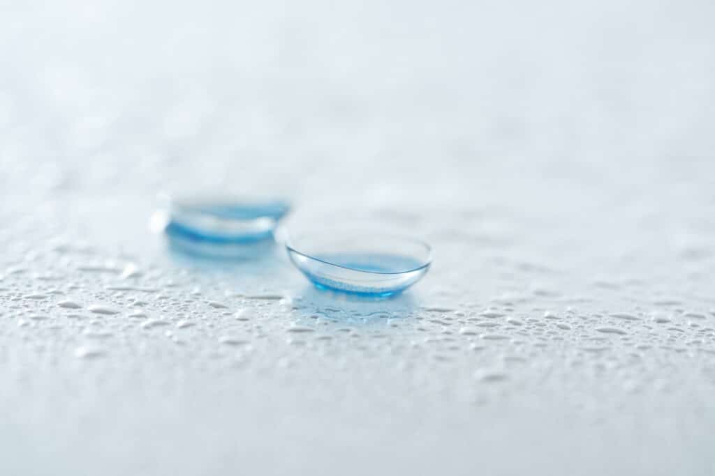 Close Up View Of Contact Lenses On White Background With Water Drops
